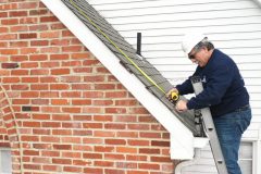 Roofing contractor measures roof
